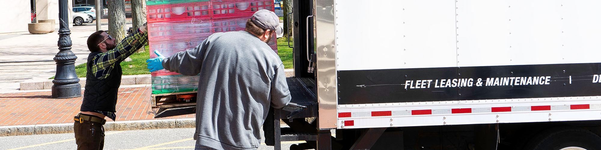 Tom Leporati of the Food Bank of Western Massachusetts (left) and Joe Mina of United Way handling a pallet of food.