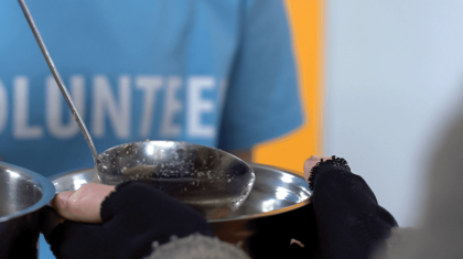 Volunteer filling a bowl of soup.