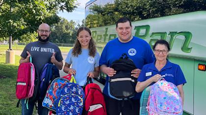United Way staff holding backpacks