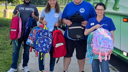 United Way staff holding backpacks